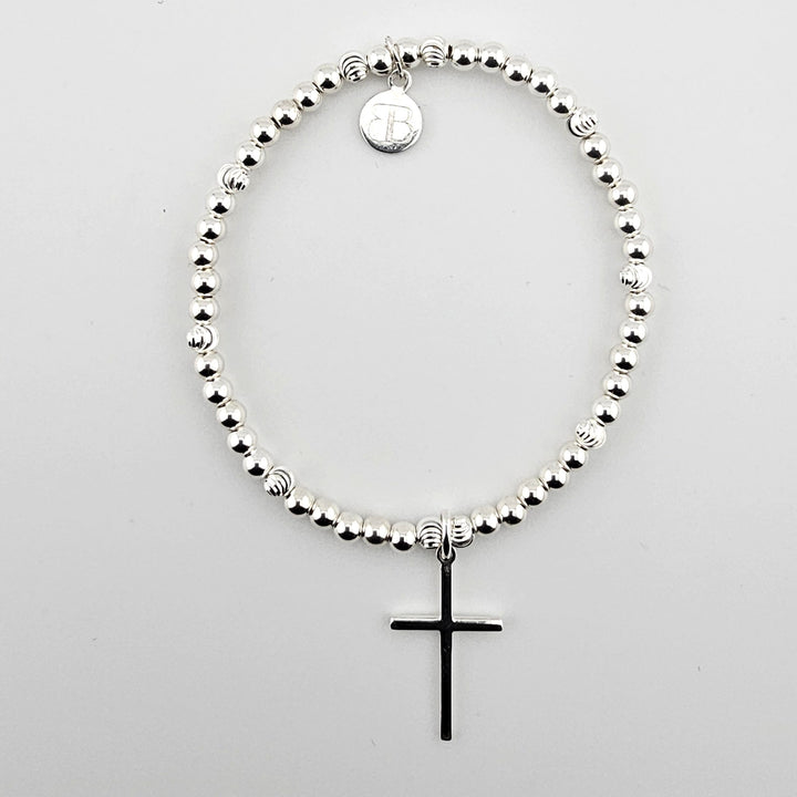 Sterling silver beaded bracelet with polished cross charm on white background.