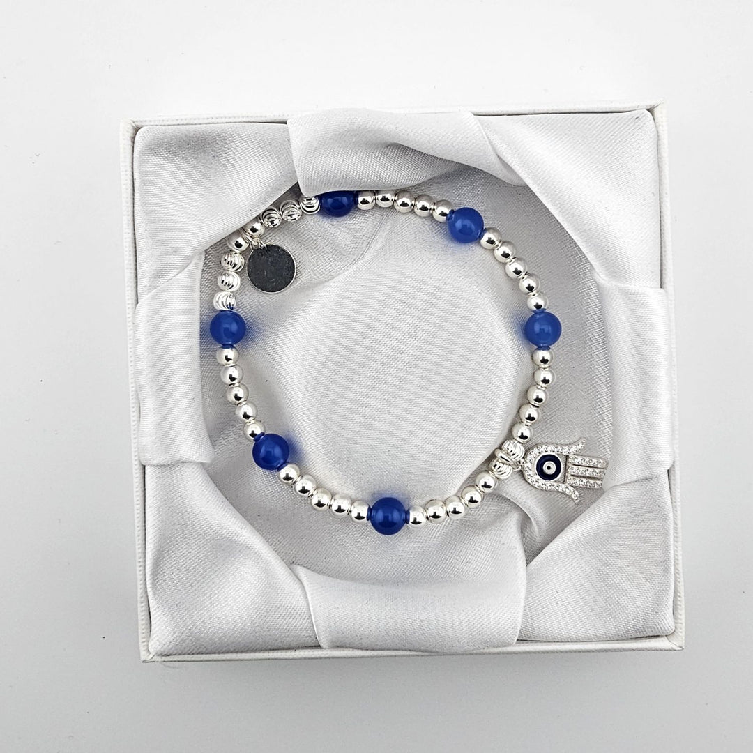 Blue agate and sterling silver beaded bracelet with evil eye charm in white box.