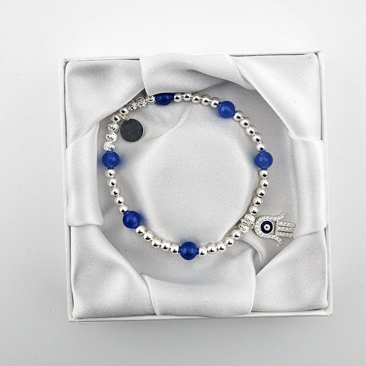 Blue agate and sterling silver beaded bracelet with evil eye charm in white box.