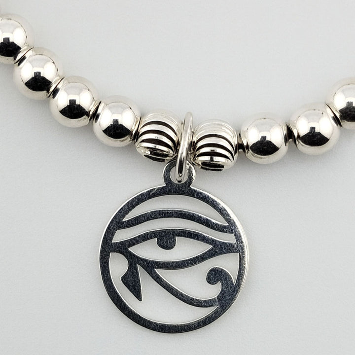 Close-up of Bessie Bae logo charm with grey agate beads and silver detail.