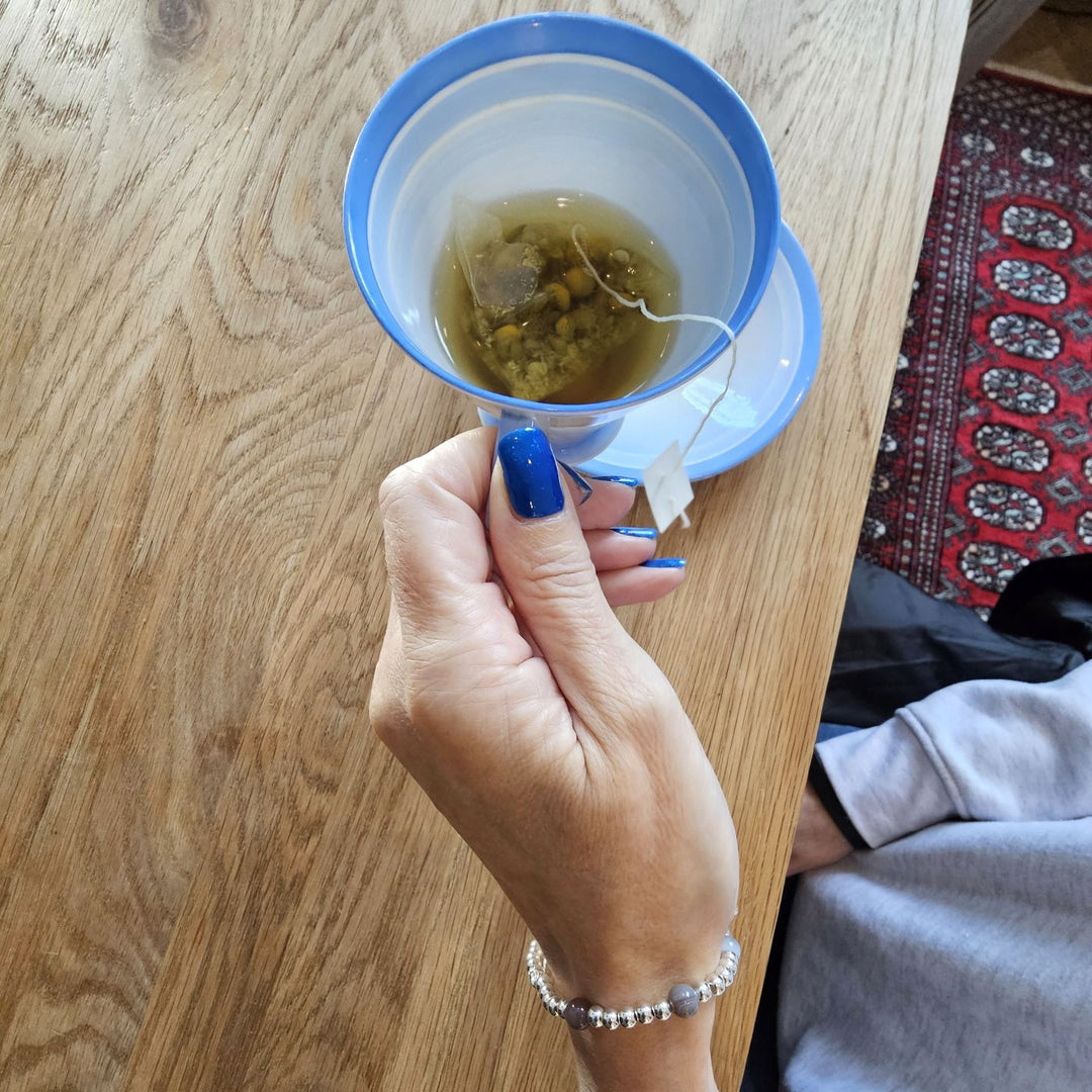 Sterling Silver Eye of Horus and Botswana Agate bracelet from Bessie Bae worn on wrist while holding a cup of tea.