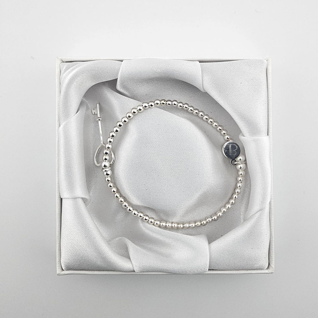 Minimalist silver bracelet with key charm for women.