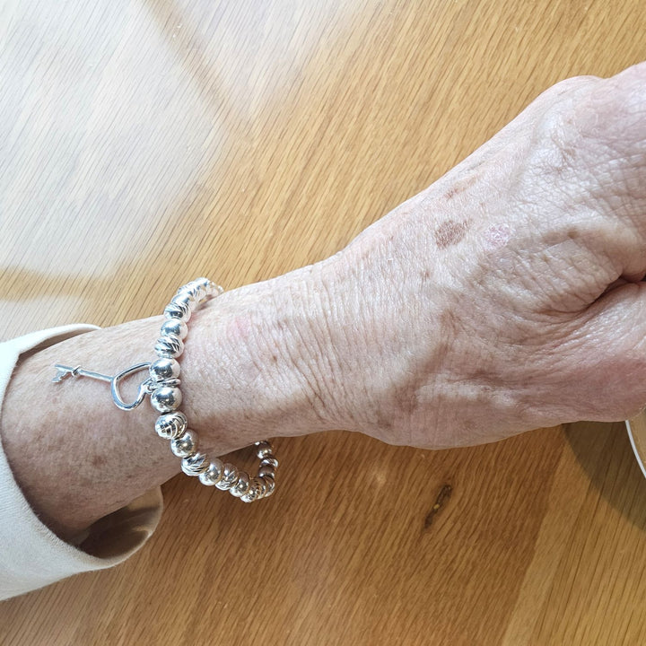 Sterling Silver Heart Key Charm Bracelet by Bessie Bae, shown on wrist with polished silver beads and delicate heart key charm.