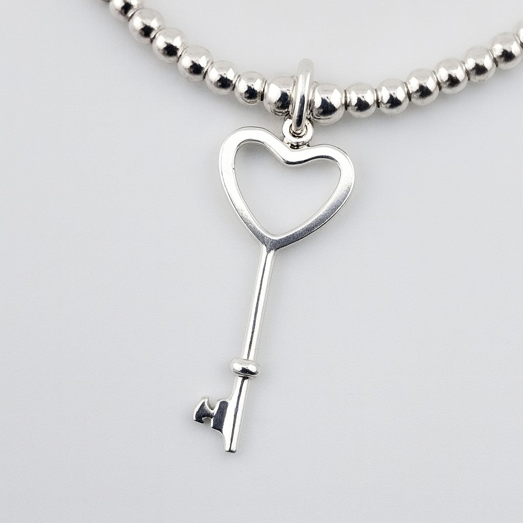 Elegant 925 silver heart key bracelet on white background.