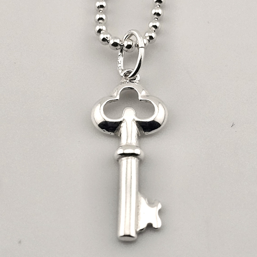Close-up of sterling silver key pendant with polished finish on delicate chain.