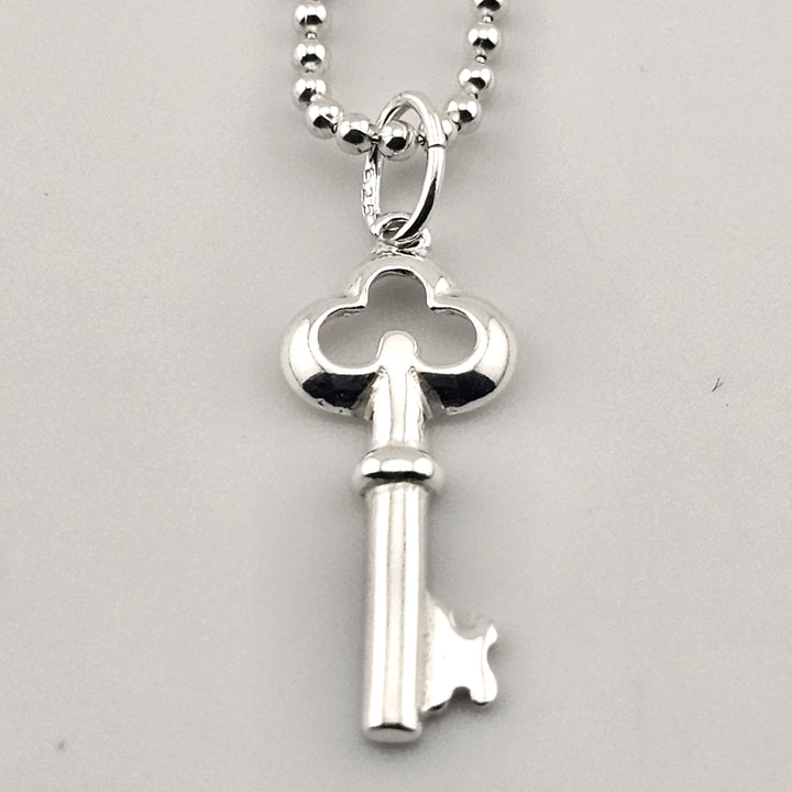 Close-up of sterling silver key pendant with polished finish on delicate chain.