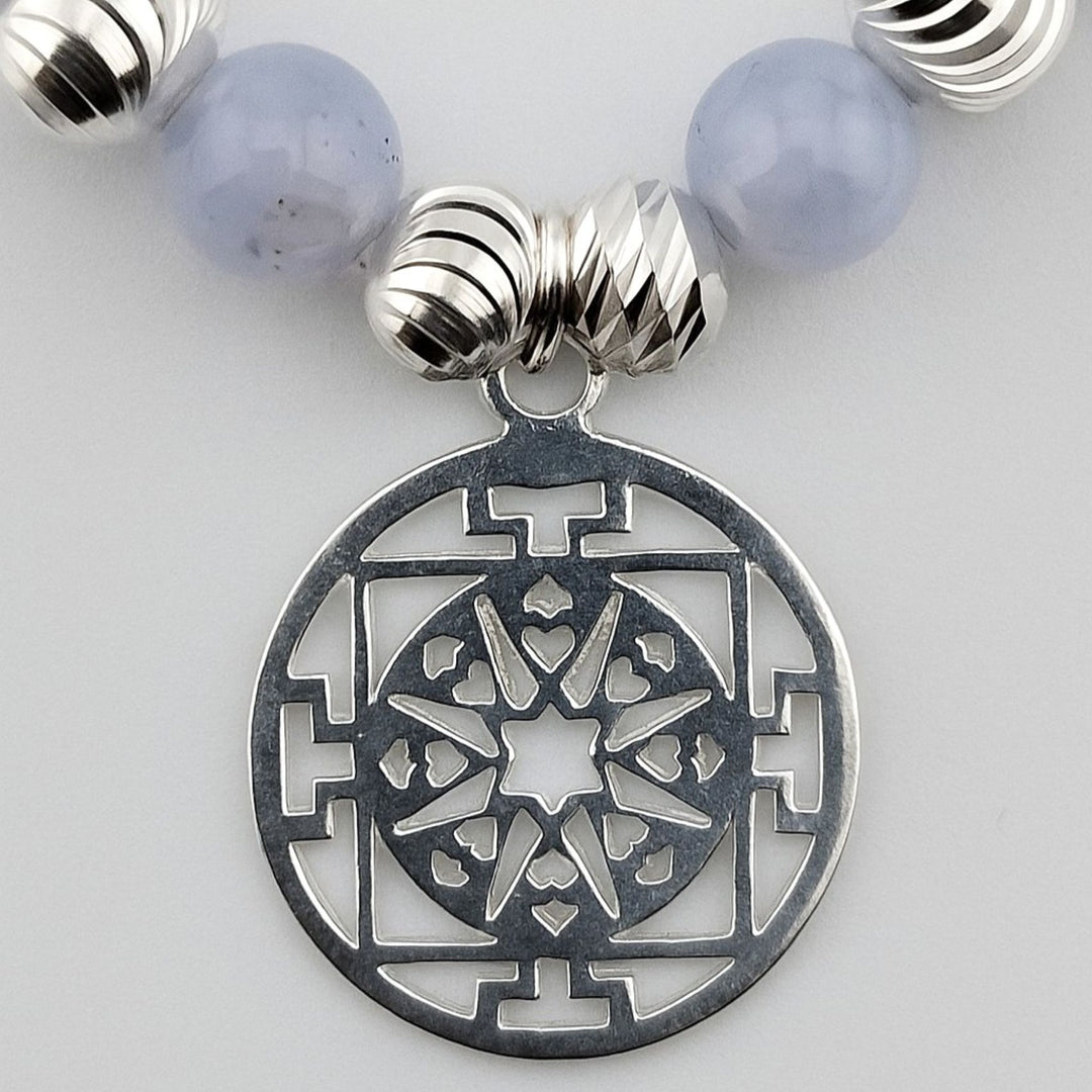 Close-up of detailed sterling silver Mandala charm on bracelet.