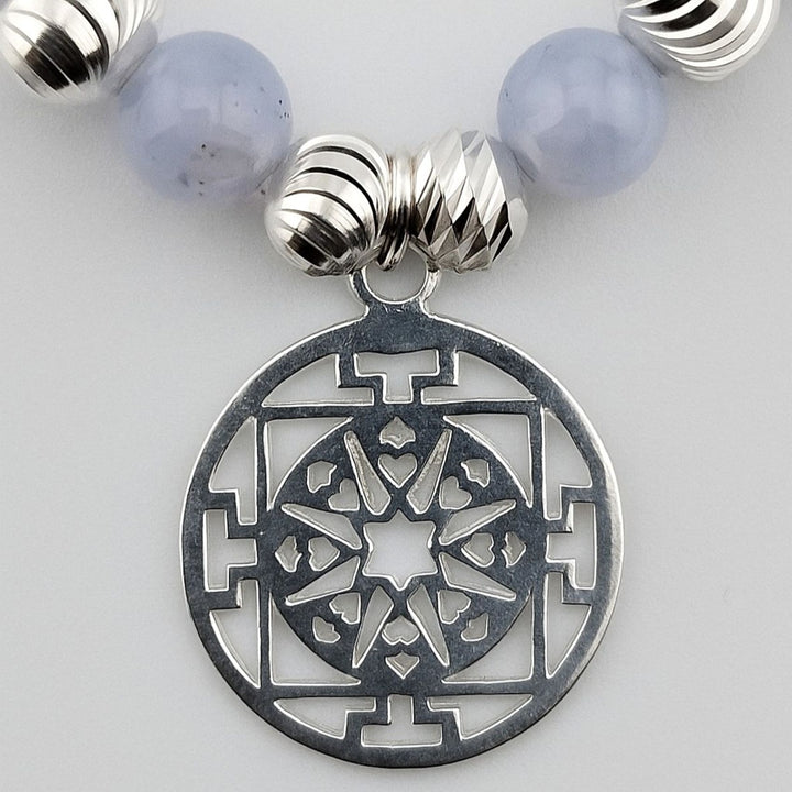 Close-up of detailed sterling silver Mandala charm on bracelet.