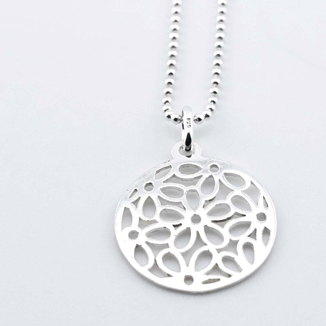 Sterling silver mandala pendant necklace with intricate cut-out design.