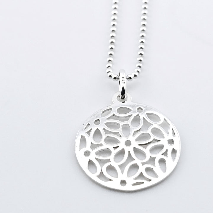 Sterling silver mandala pendant necklace with intricate cut-out design.