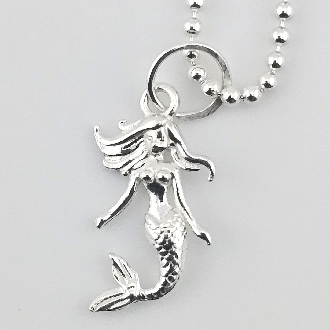 Close-up of sterling silver mermaid pendant showing detailed tail and flowing hair.