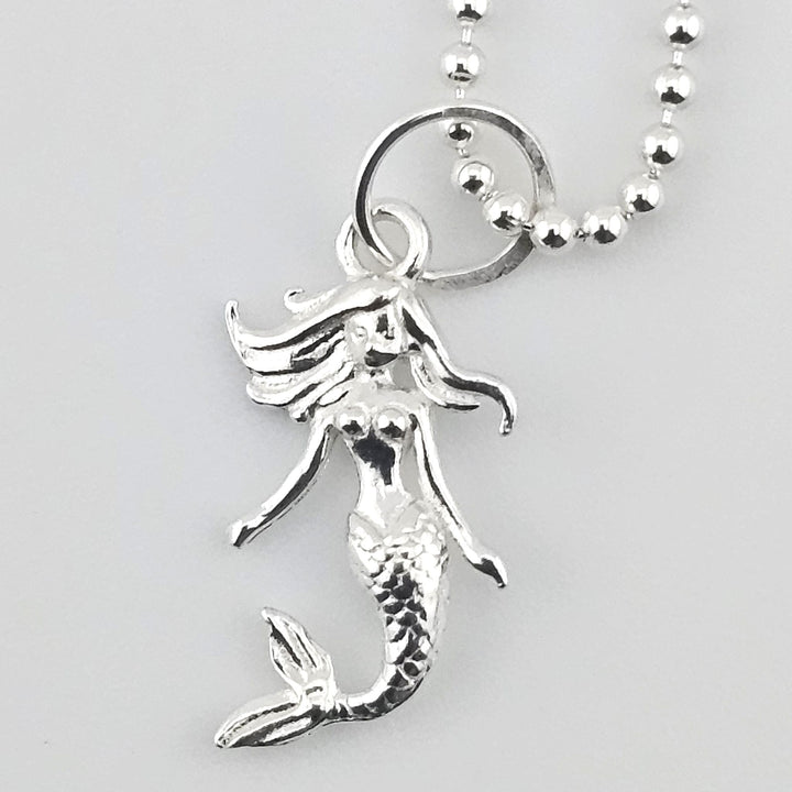 Close-up of sterling silver mermaid pendant showing detailed tail and flowing hair.