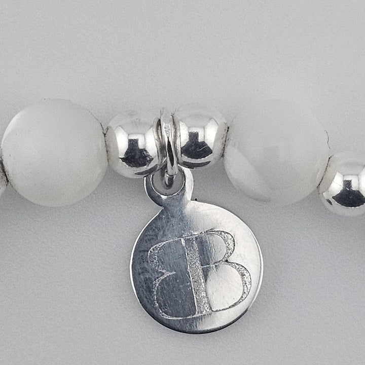 Sterling silver wishbone charm bracelet with natural mother of pearl beads.