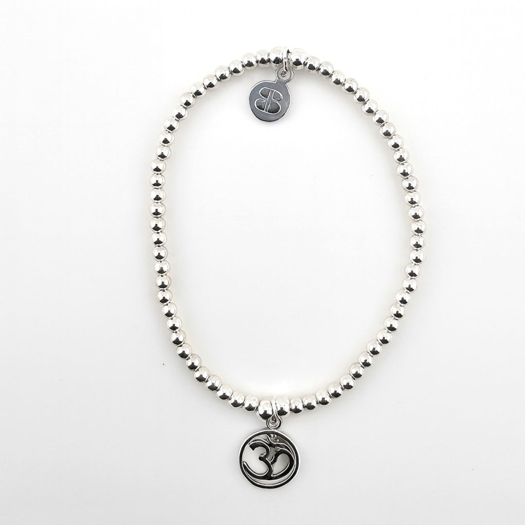 Sterling silver beaded bracelet with Om symbol charm on white background.