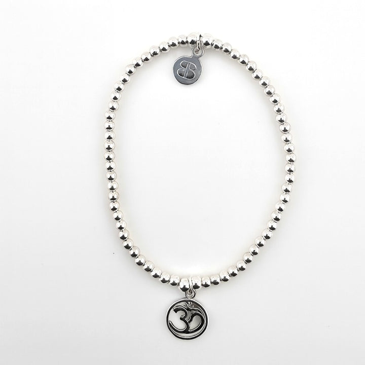 Sterling silver beaded bracelet with Om symbol charm on white background.