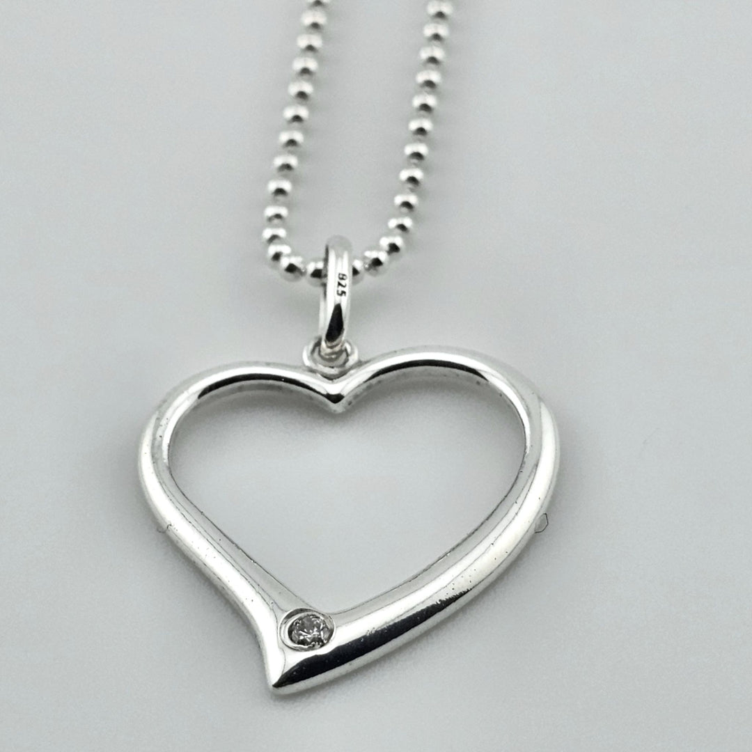 Minimalist sterling silver heart necklace, open design with gemstone detail.