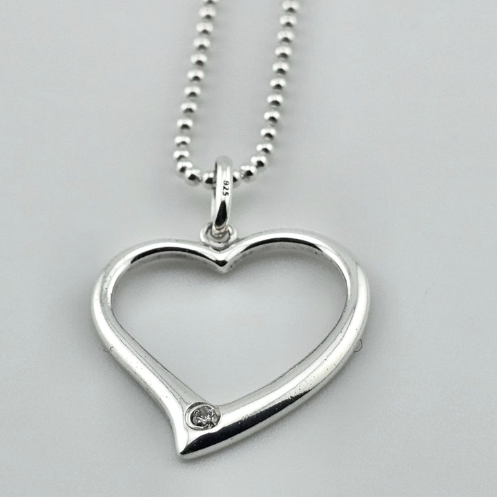 Minimalist sterling silver heart necklace, open design with gemstone detail.