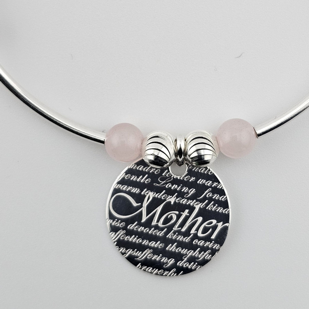 Close-up of engraved “Mother” charm with pink gemstone beads.
