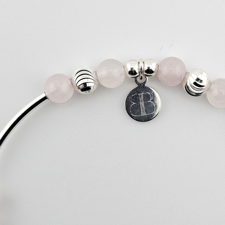 Bessie Bae logo charm with rose quartz and silver beading detail.