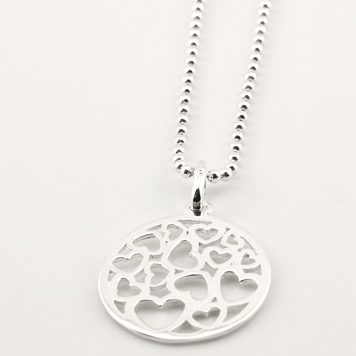 Elegant sterling silver necklace with round pendant and cut-out hearts pattern.