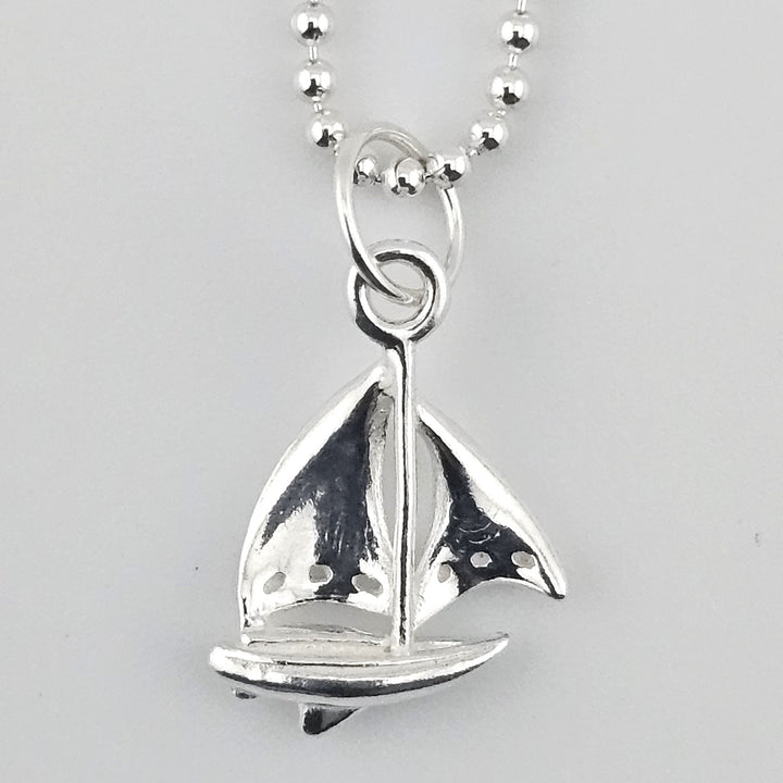 Close-up of sterling silver sail boat charm detailing.
