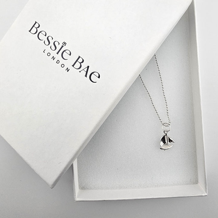 Sterling silver sail boat necklace with complimentary Bessie Bae gift packaging.