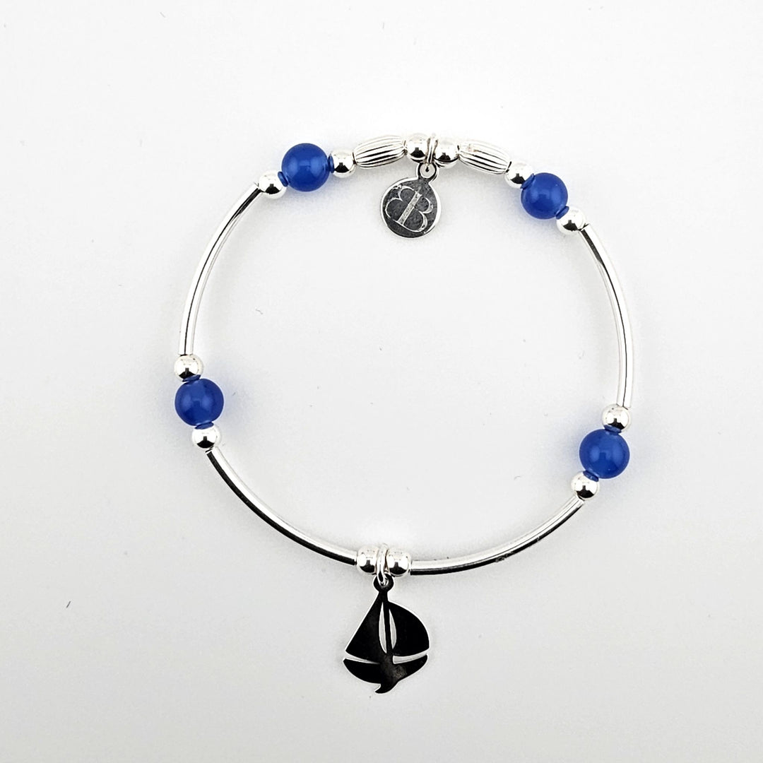 Sterling silver sailboat charm bracelet with blue beads on white background.