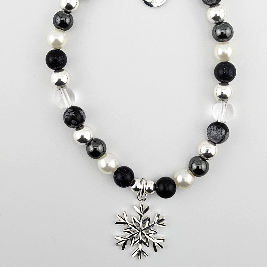 Sterling silver snowflake charm bracelet with obsidian and mother of pearl beads.