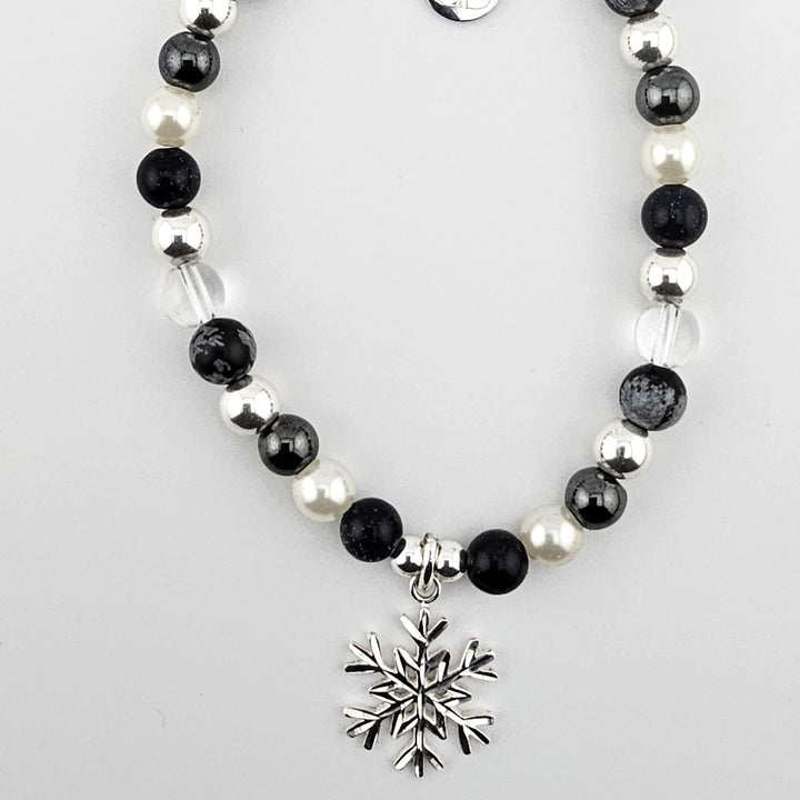 Sterling silver snowflake charm bracelet with obsidian and mother of pearl beads.