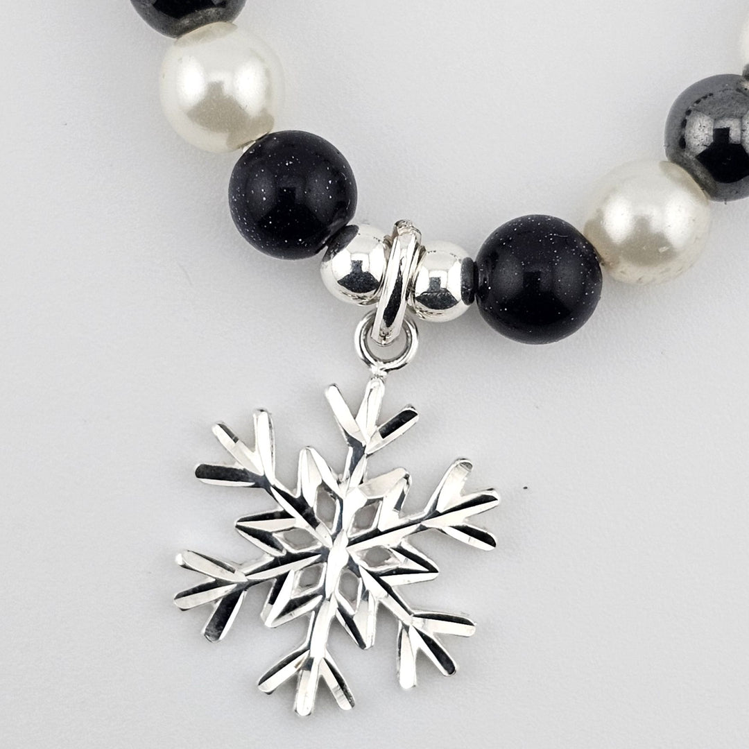 Winter-inspired gemstone bracelet featuring snowflake charm.
