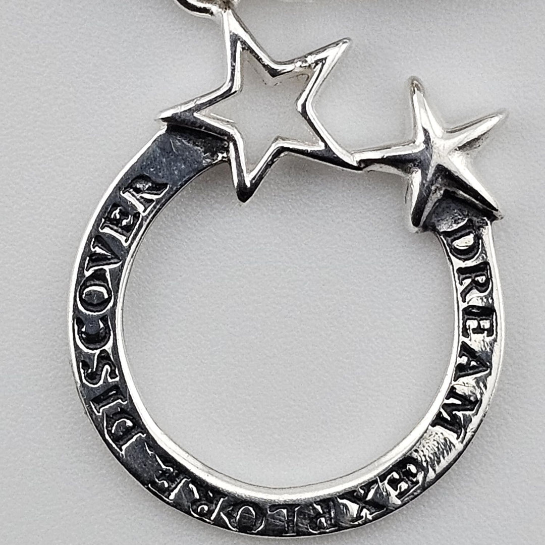 Close-up of silver Dream Explore Discover charm with two star accents on sterling silver bracelet by Bessie Bae.