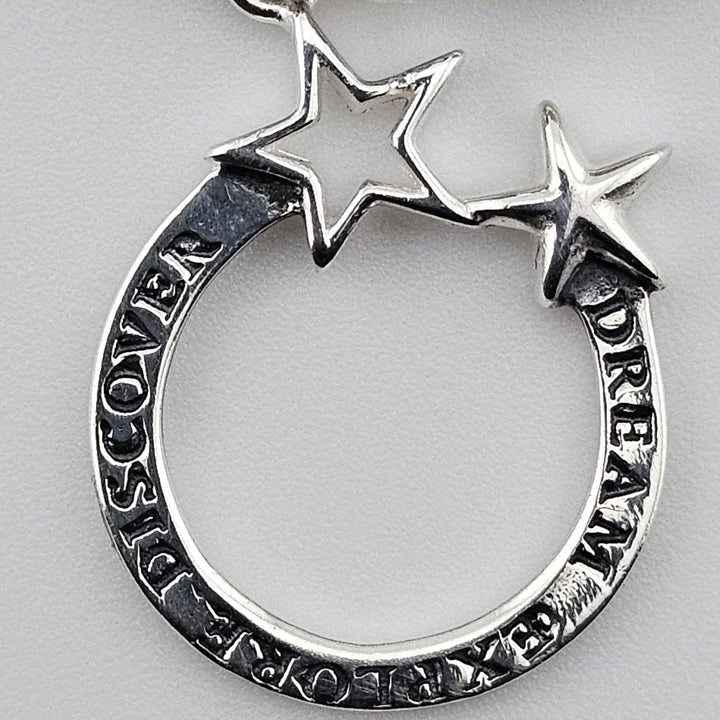 Close-up of silver Dream Explore Discover charm with two star accents on sterling silver bracelet by Bessie Bae.
