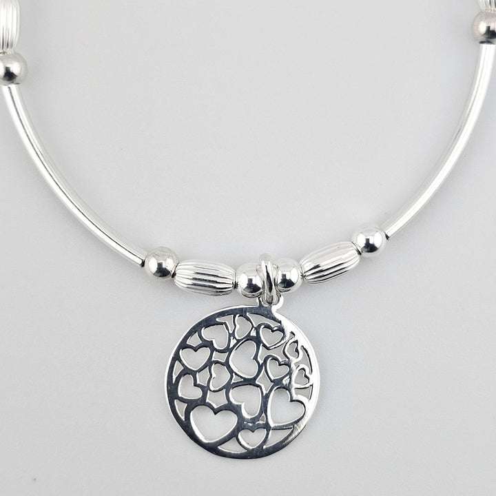 Elegant silver bracelet featuring heart tree pendant.
