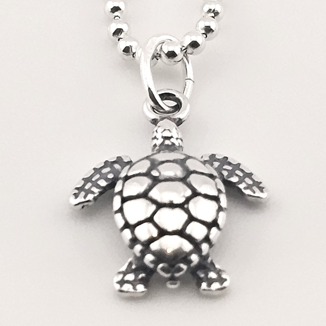 Close-up of sterling silver sea turtle necklace, ocean-inspired jewellery.