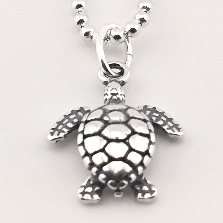 Close-up of sterling silver sea turtle necklace, ocean-inspired jewellery.