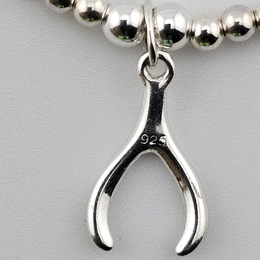 Close-up of sterling silver wishbone charm engraved 925 hallmark.