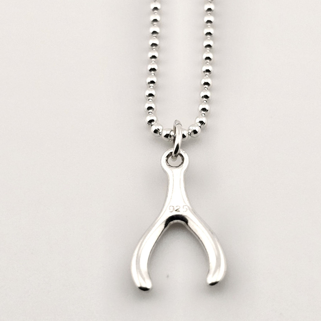 Close-up of sterling silver wishbone necklace, minimalist lucky pendant.