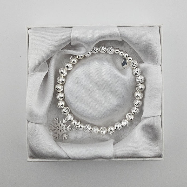 Top view of sterling silver beaded snowflake charm bracelet in gift box.