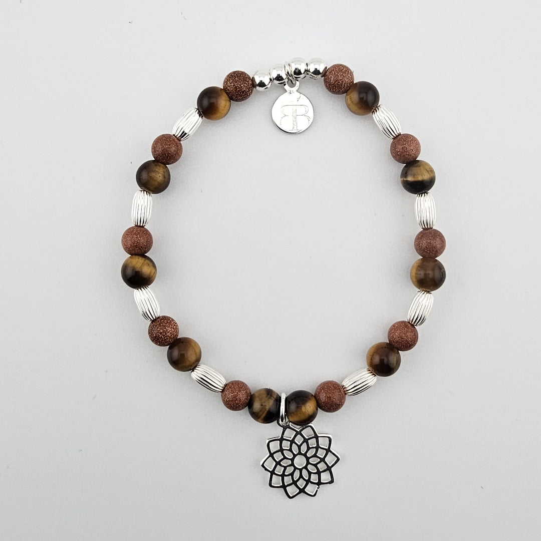 Tiger’s eye and goldstone gemstone bracelet with sterling silver lotus charm on white background.