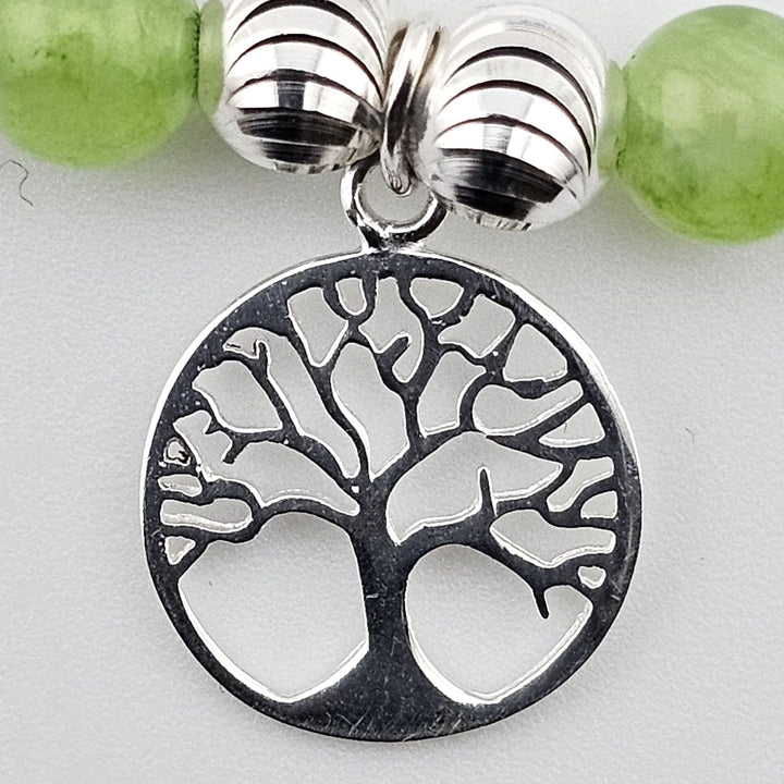Close-up of sterling silver Tree of Life charm on green aventurine bracelet.